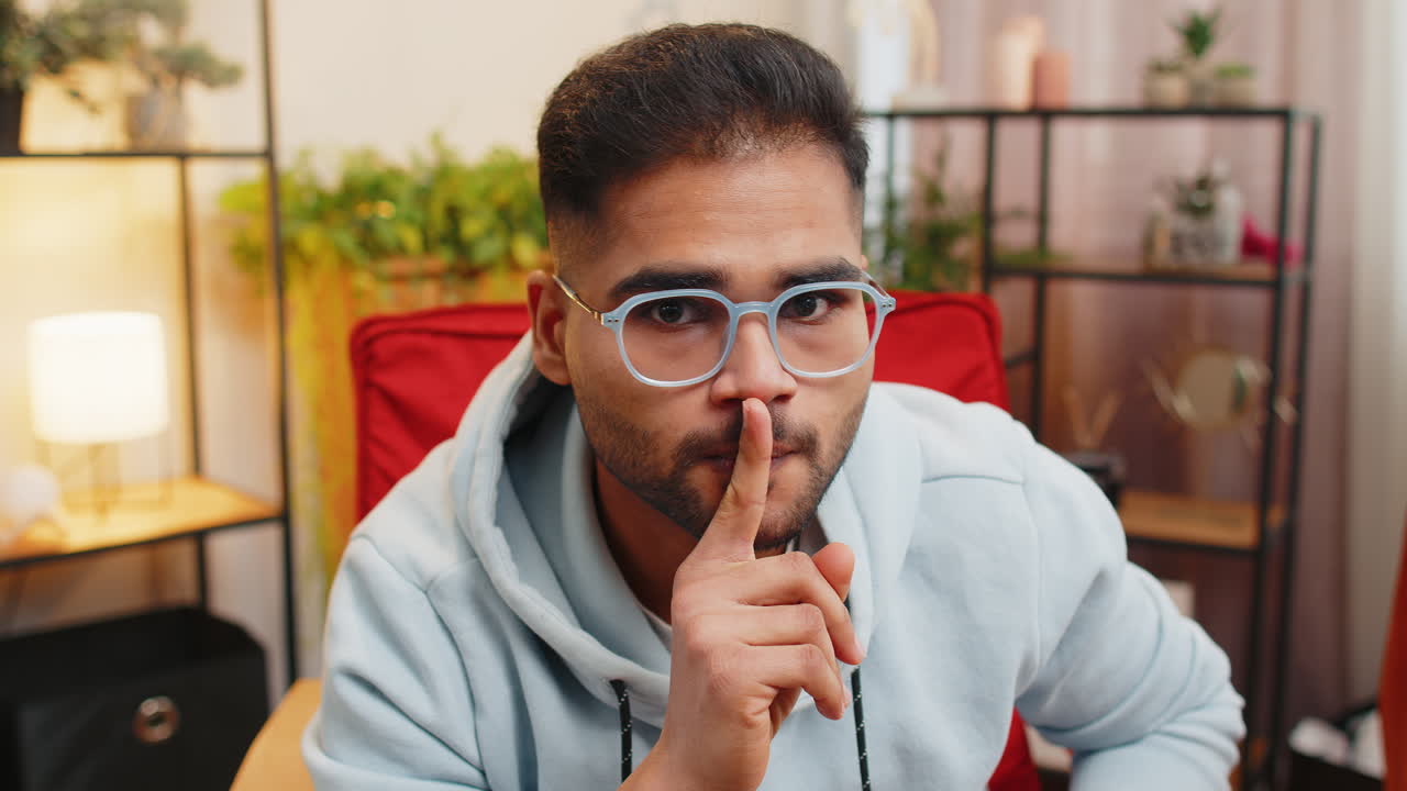 Indian man presses finger to lips makes silence hush sign do not tells gossip secret quiet