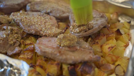 untar mostaza dijon en terrón recién cocido sobre papas y cebollas al horno