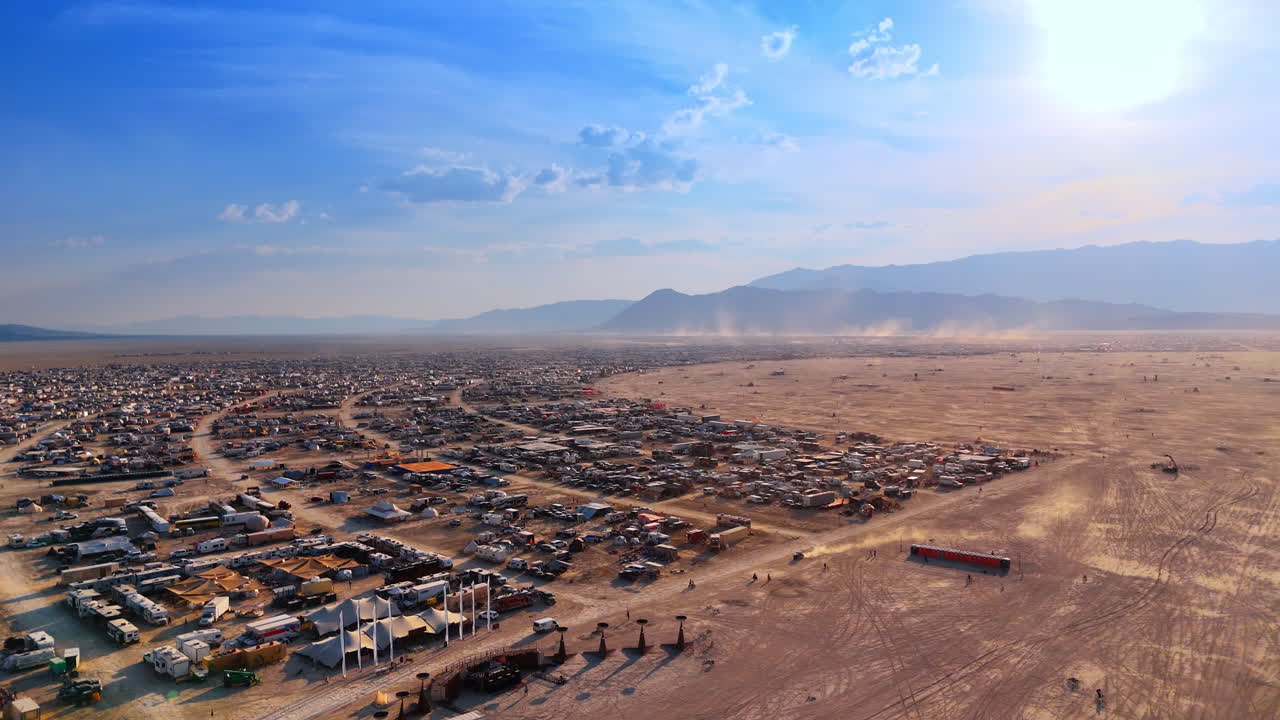 Ampio panorama aereo del confine di una città nel deserto e polvere. Veduta dall'alto del limite tra un insediamento temporaneo e la distesa aperta con scie di polvere.
