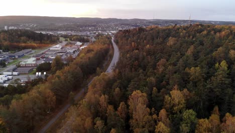 aerial drone flying above road to gothenburg in suburbs area, autumn forest, day