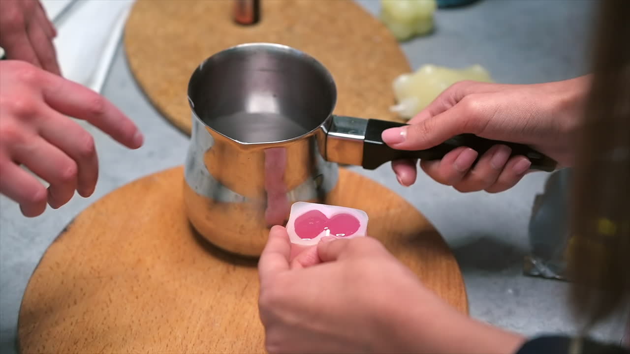 A woman occupied with hand made candles production, pouring melted wax into the mold. Slow motion