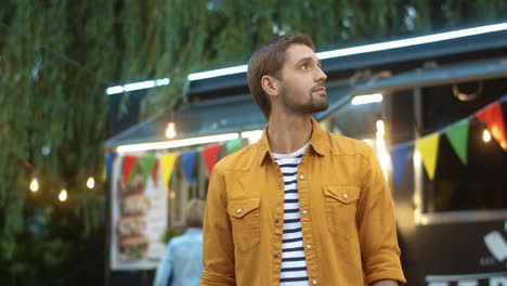 Portrait-Of-Attractive-Young-Guy-Turning-Face-To-Camera-And-Smiling-Cheerfully-Outdoors