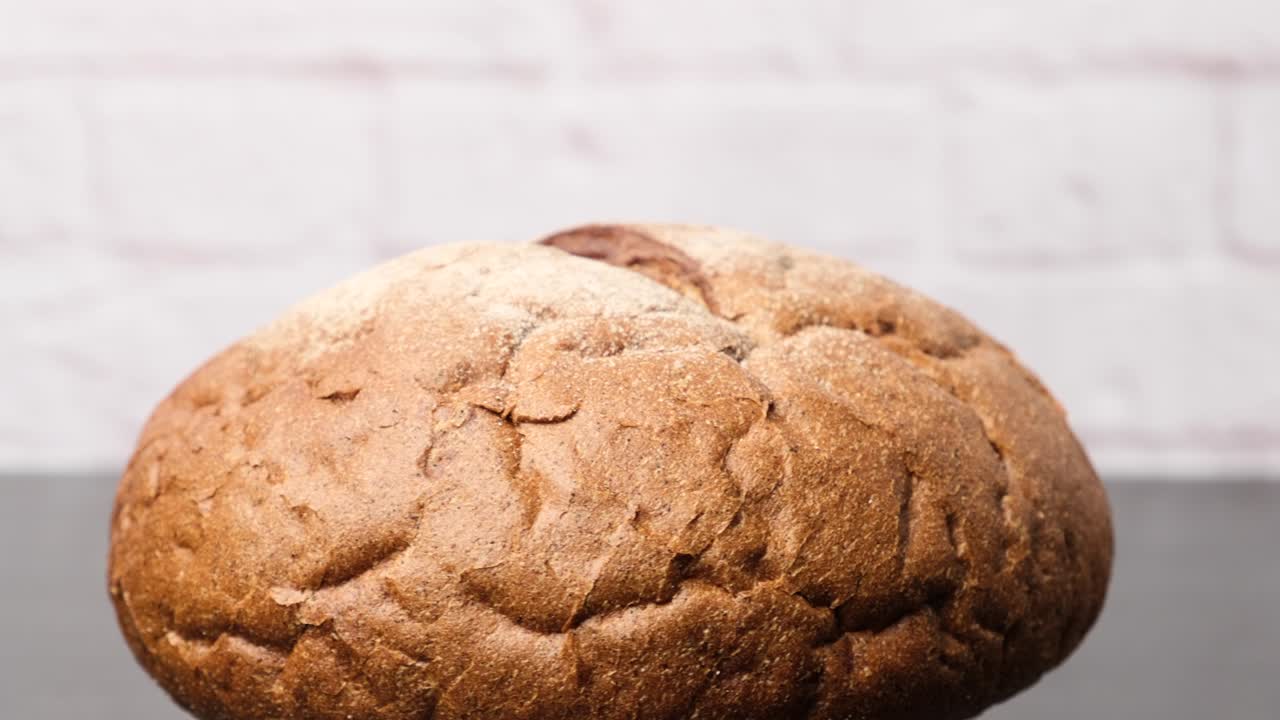 baked round loaf of rye flour bread rotates on its axis