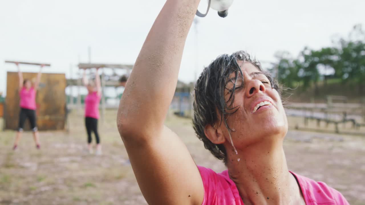 mujer de raza mixta vertiendo agua en su cara en el campamento de entrenamiento