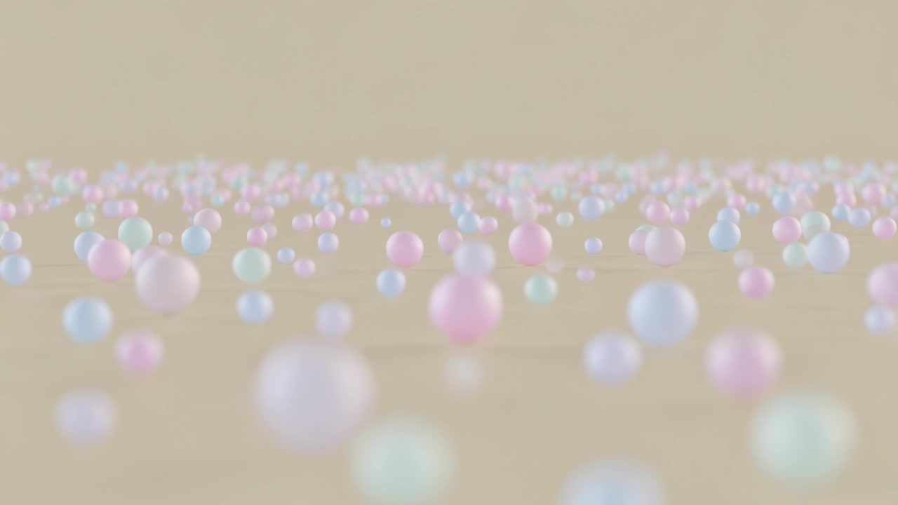 La telecamera che si sposta mette a fuoco sfere lucide pastello a metà campo sul pavimento dello studio con effetto bokeh.