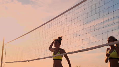 Gruppe-Junger-Mädchen,-Die-Bei-Sonnenuntergang-Oder-Sonnenaufgang-Beachvolleyball-Spielen