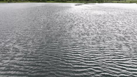 reveal from an alpine lake over the water to a mountain retreat next to a large river in the mountains of silverthorne colorado on a hazy day aerial dolly raise tilt