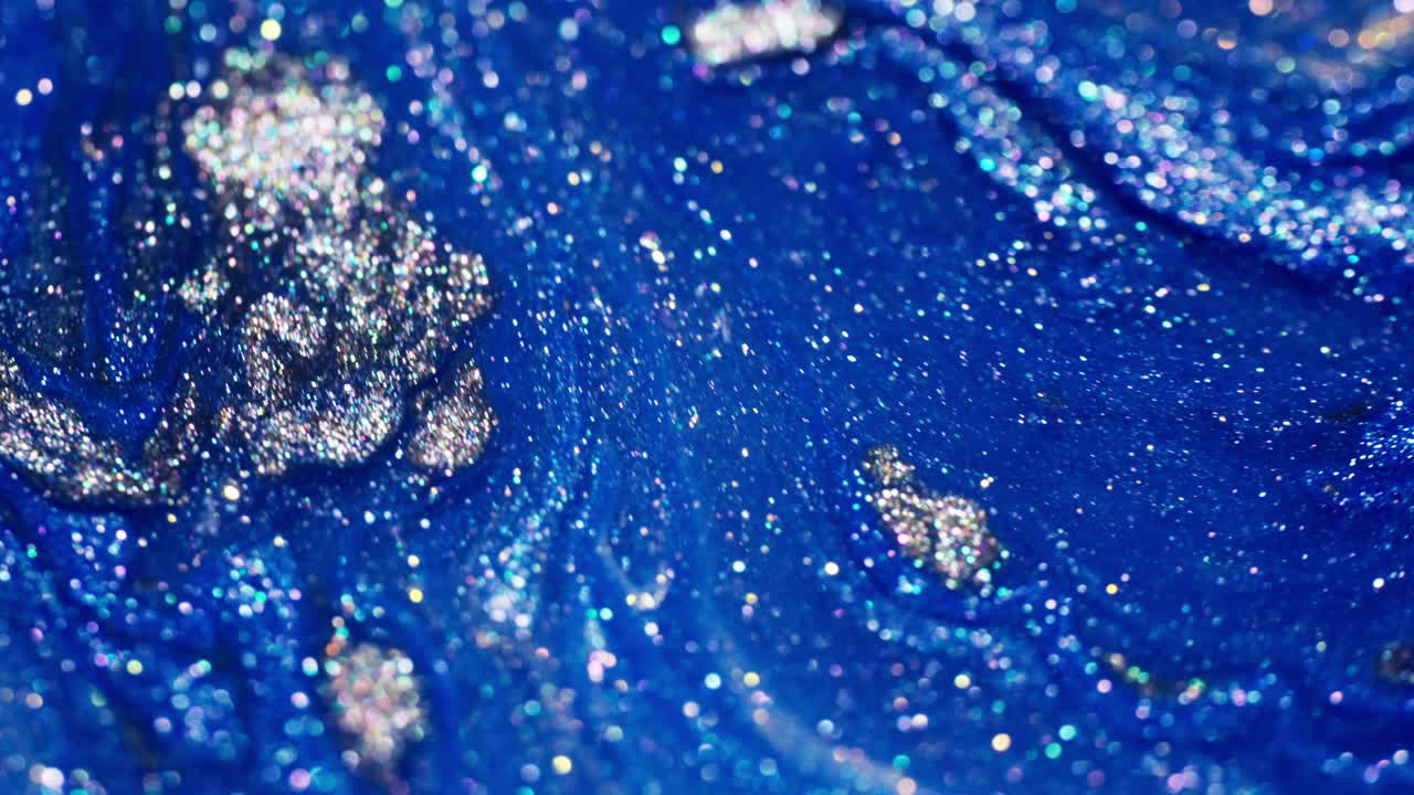 Flowing blue ink and glitter blending together in a mesmerizing macro shot