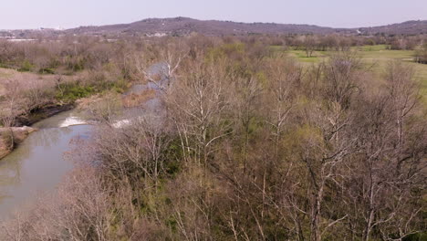 Ascending-shot-overhead-of-bare-woodlands-beside-West-Fork-White-River-Pump-Station