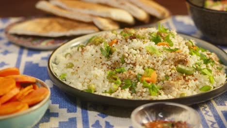 putting cooked couscous with chicken on table close-up. arabian cuisine. pita and bulgur on background. traditional middle eastern culture. delicious rice with meat. homemade food concept