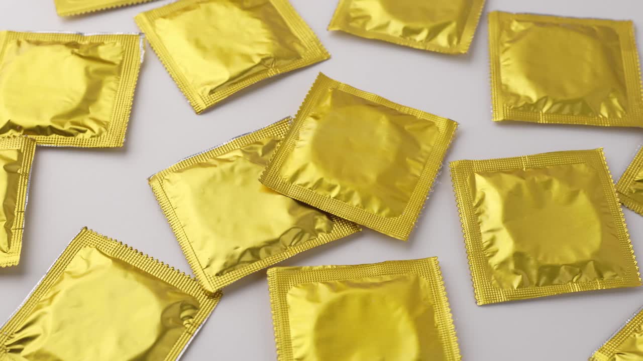 Pacchetti di preservativi color oro su sfondo bianco