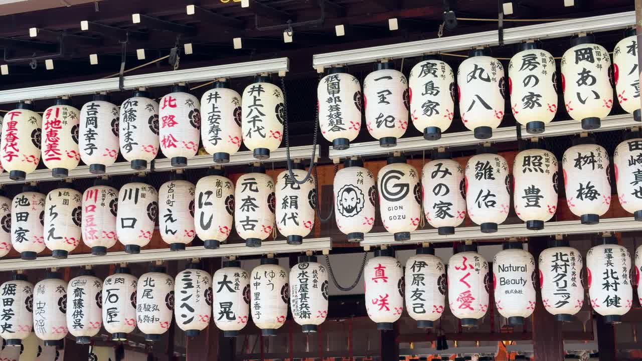 File di lanterne di carta bianche con calligrafia kanji nera pendono in un santuario di Kyoto.