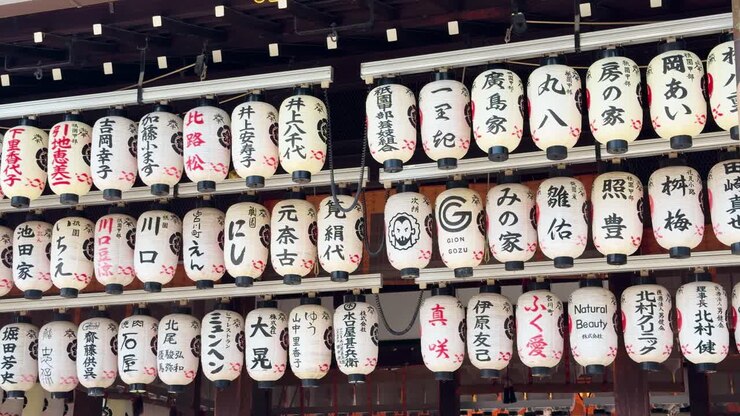 File di lanterne di carta bianche con calligrafia kanji nera pendono in un santuario di Kyoto.