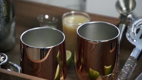 slow zoom in to copper cups with lime juice in the background drinking glasses wine cups copper cups