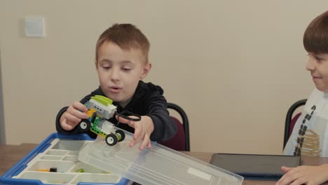 children intently focused on assembling parts from a robotics kit, with a tablet displaying instructions, promoting stem learning and creativity