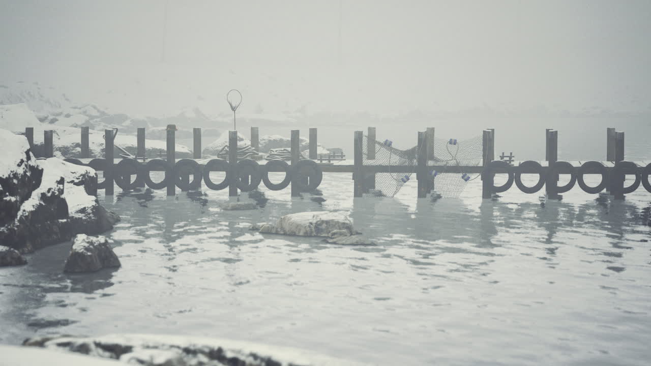 Snowy landscape with a dock and still water under overcast skies