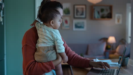 trabajo remoto, portátil y madre con bebé por la noche