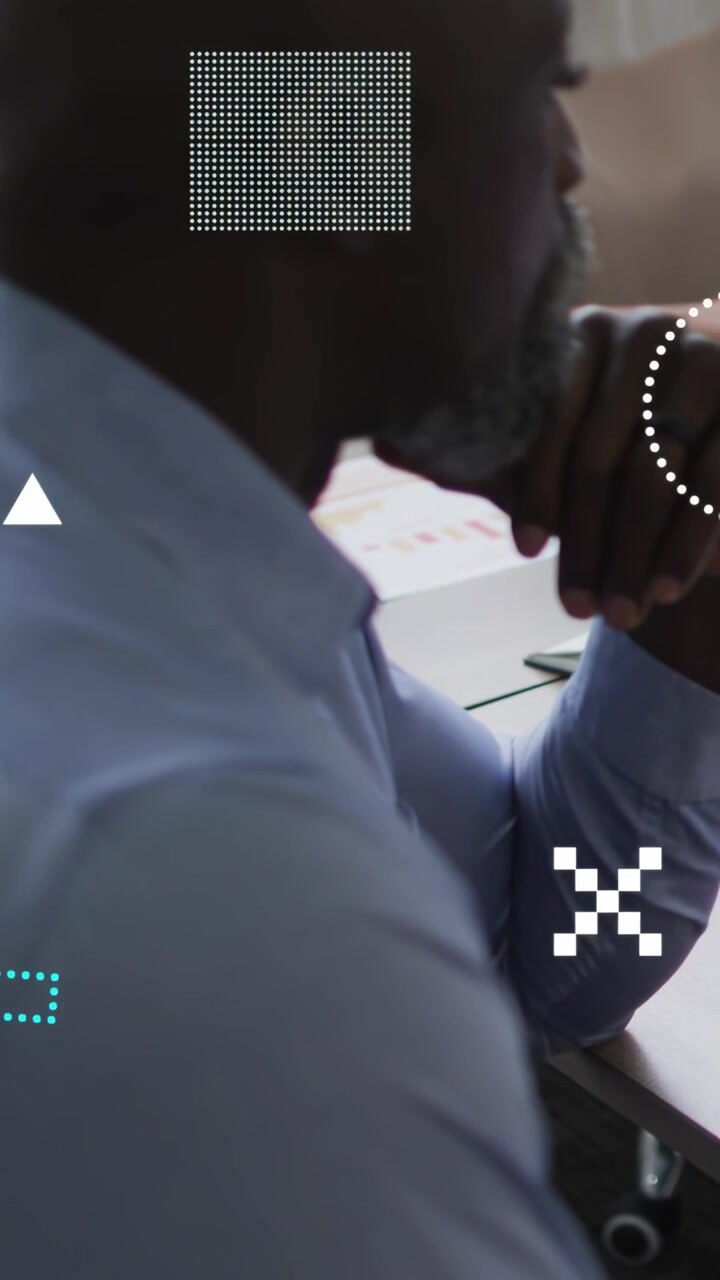 Vertical video: Male leaning at desk, arm causing HUD overlays obscuring face analyzing finance