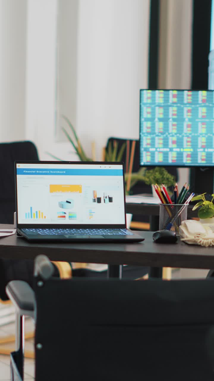 Vertical video Company workspace with nobody in and business figures on computer monitors