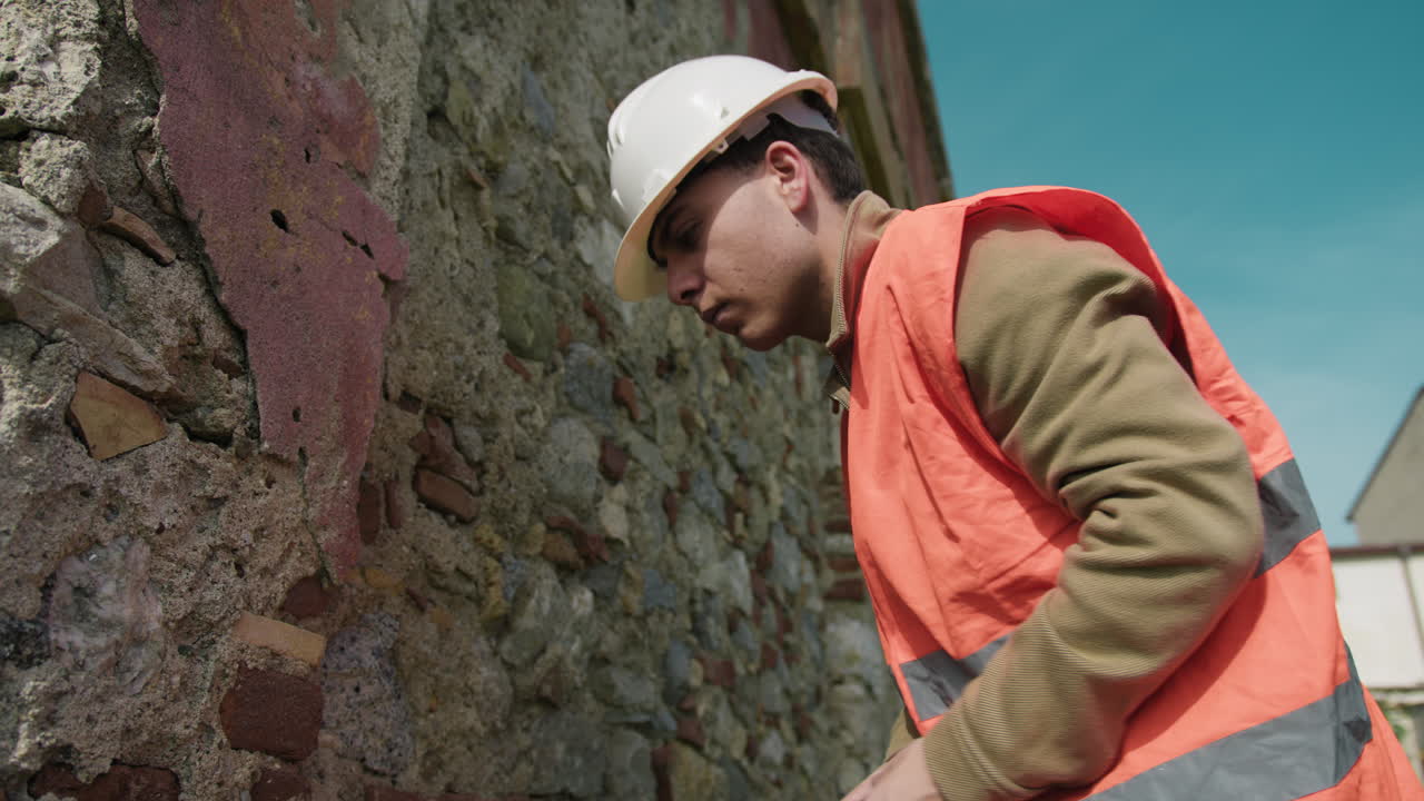 Construction Worker Measuring And Testing An Old Wall Outdoor
