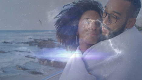 woman and man standing on coastal railing wrapping blanket, showing cosmic stars overlay for tech