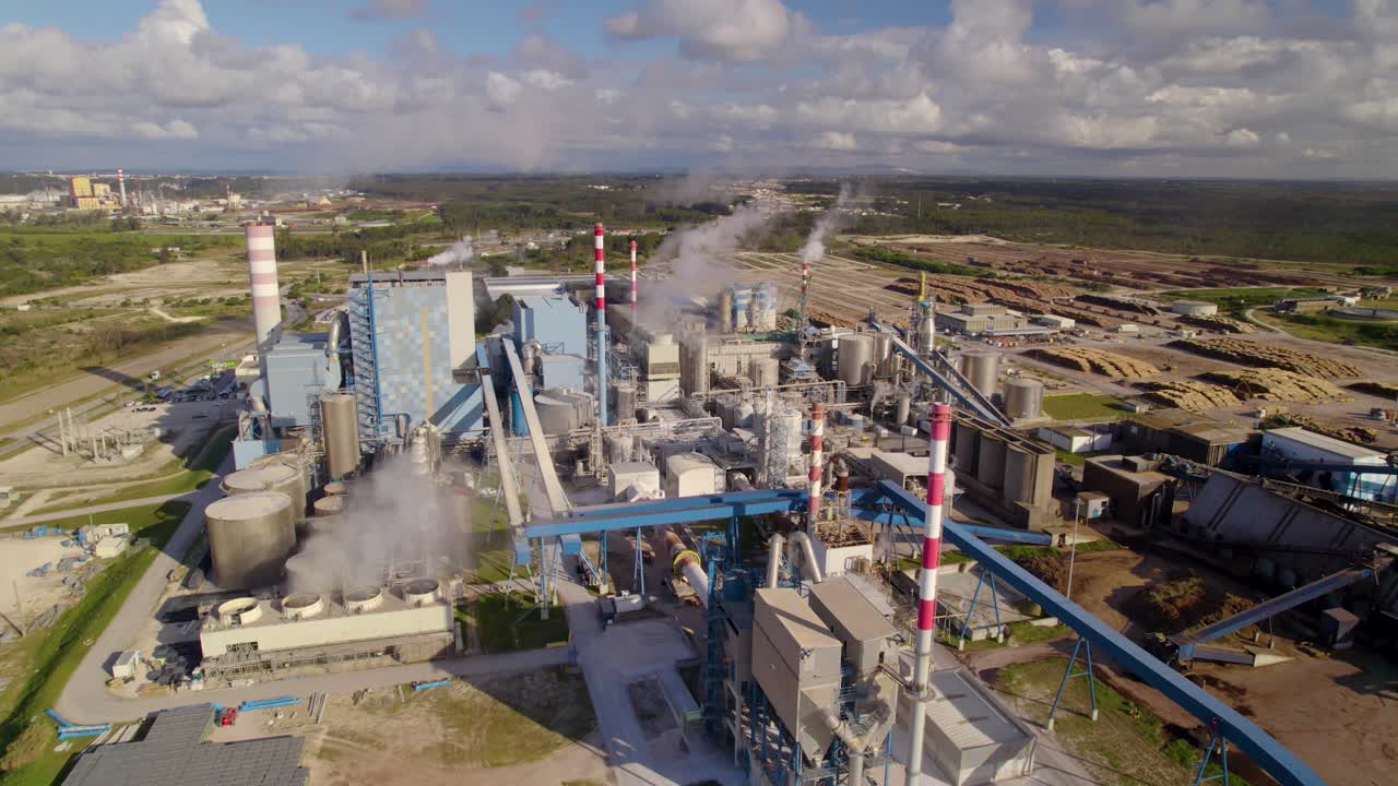 órbita aérea sobre la gran planta industrial en un día soleado - una moderna fábrica de celulosa con mucho humo