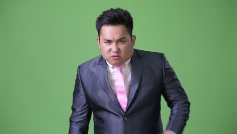초록색 배경에 젊은 잘생긴 과체중 아시아 사업가