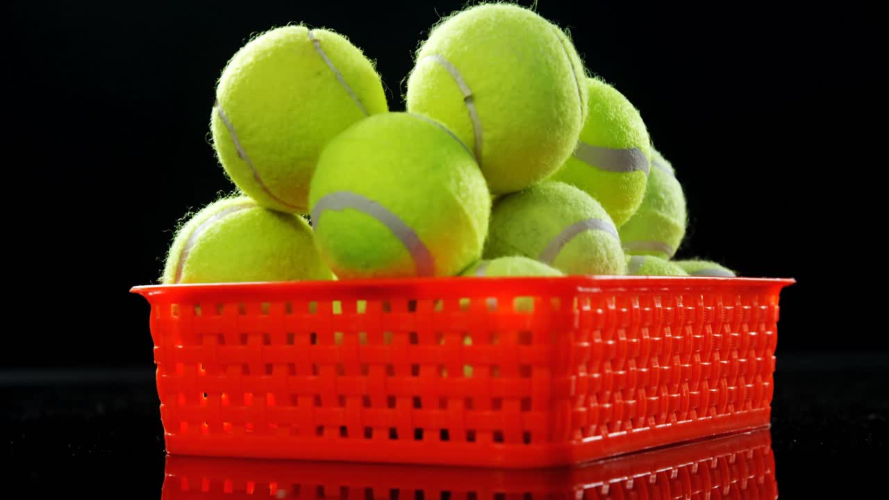 Basket full of tennis ball against black background