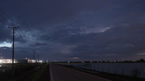 Electric-storm-behind-power-cables-strung-along-roadside