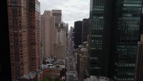 flying between buildings towards the times square in cloudy, new york, usa - aerial view