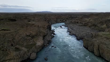 Luftfluss-Vom-Aldeyjarfoss-Wasserfall-In-Nordisland-Im-Sommer,-Umgeben-Von-Basaltsäulen-In-Einer-Wunderschönen-Braunen-Landschaft