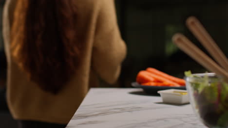 close up of woman at home in kitchen preparing healthy vegetarian or vegan meal eating bowl of salad leaves with seeds and dressing 1