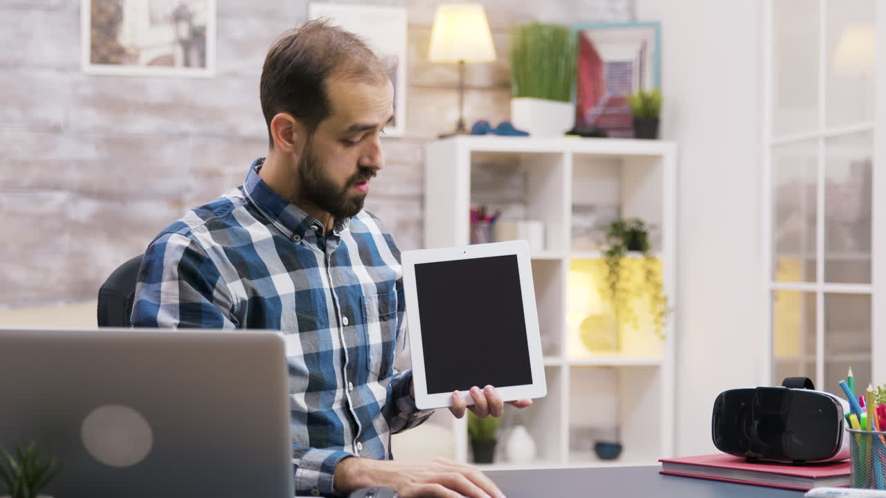 Man presenting with tablet in home office