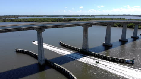 aerial drone shot of a jetski going under a causeway on the indian river lagoon in sebastian fl