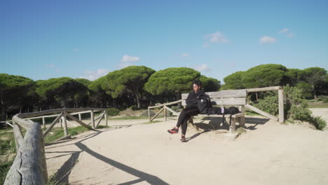 young woman resting on a bench and looking at the ocean after hiking