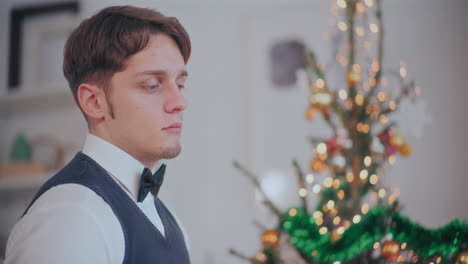 thoughtful man with decorated christmas tree in background at home