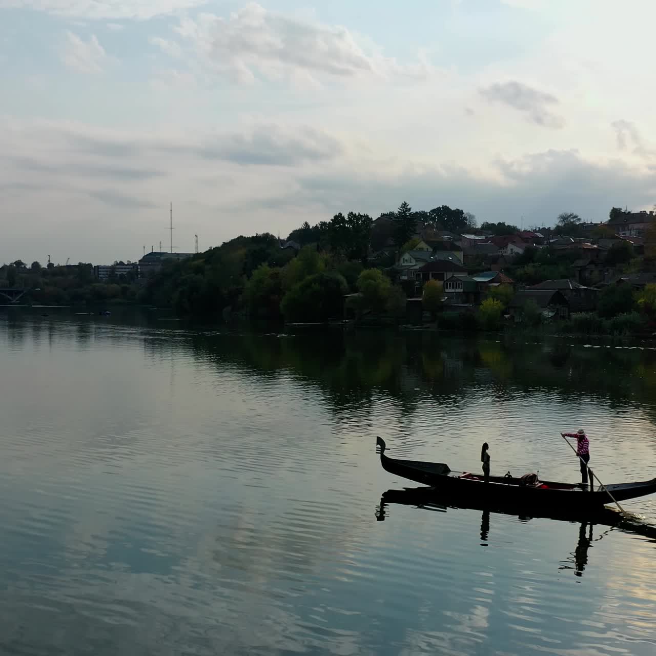 Gondola on water at sunset. Woman floating in a boat along the river on the city background. Gondolier in costume in gondola.