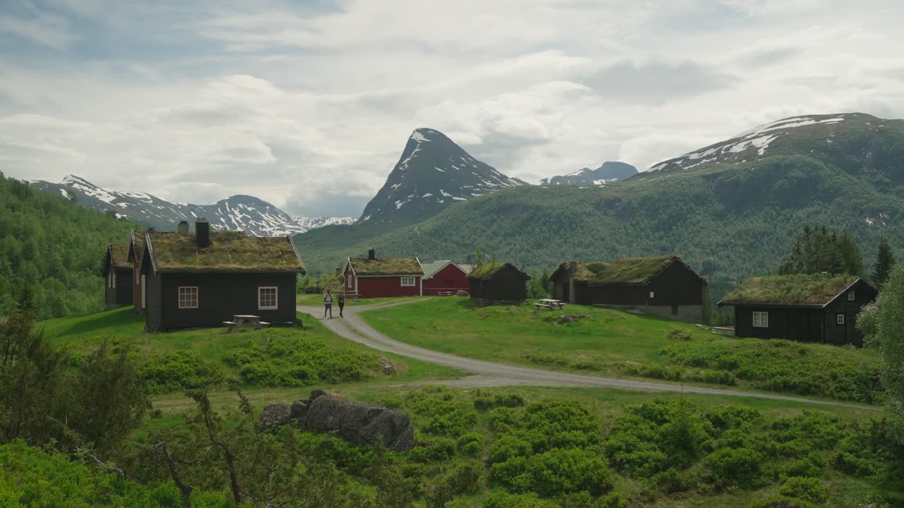 Pittoresk landsby med tradisjonelle trehus i Norge, med fjell i bakgrunnen.