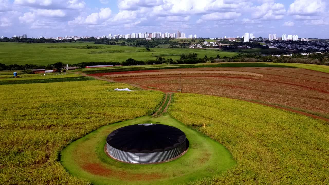 vista aérea, tanque de agua y un campo de maíz, con la ciudad de campo grande en el fondo