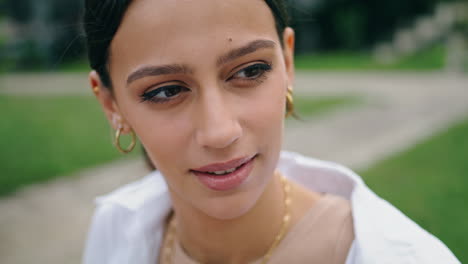 Smiling-girl-speaking-at-park-vertical-close-up.-Brunette-woman-telling-story