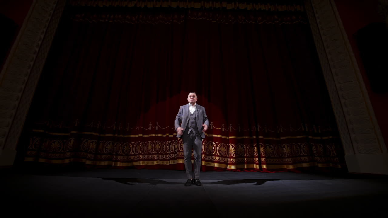 Showman dances on a stage. Senior male entertainer, presenter or actor on stage. Selective focus on a male in suit.