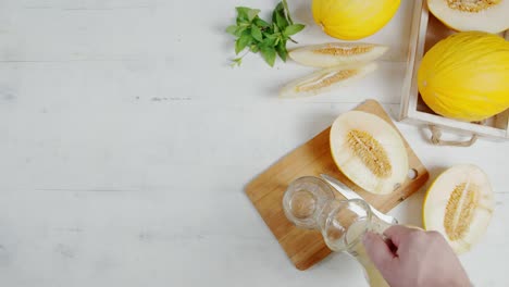 man's hand pouring the melon juice into a glass.