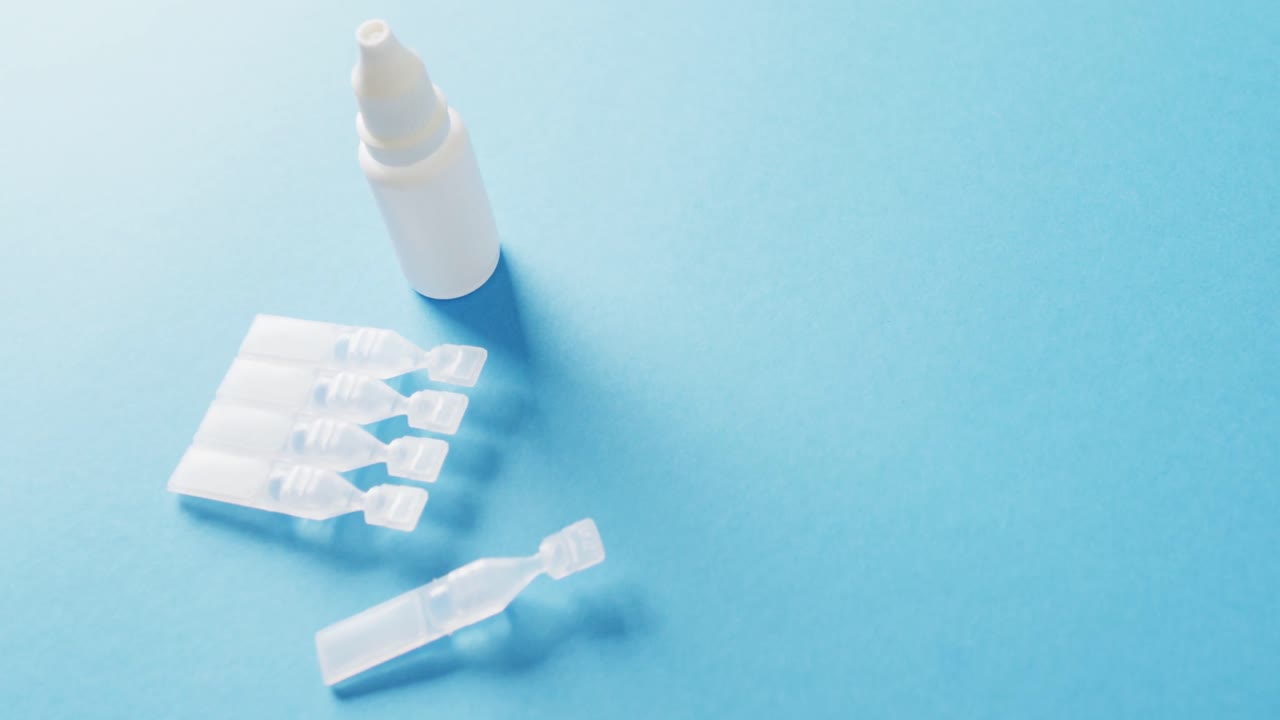 Video of saline caplets and dropper bottle on blue background with copy space