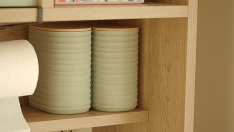 toilet paper and storage canisters on a wooden shelf