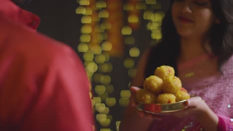 cerca de una mujer dándole ladoo a un hombre para comer celebrando el festival de diwali 1