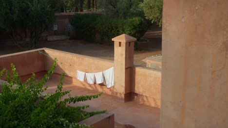 static shot of white cloth hanging to dry within stunning moroccan courtyard architecture in marrakech, morocco, during golden hour, showcasing warm light and cultural detail