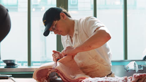 young male butcher carefully preparing a large cut of meat