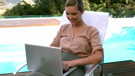 Empresaria-Sonriente-Usando-Laptop-Junto-A-La-Piscina