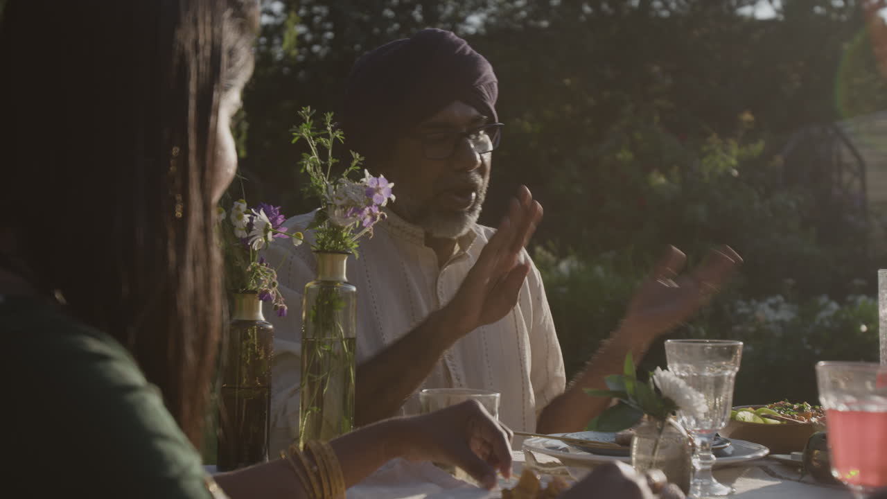 Indian family enjoying an outdoor dinner and conversation at sunset