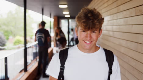 Portrait-Of-Male-Student-Walking-Into-Focus-Outside-Building